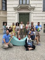 Die Mitarbeitenden der Medienbearbeitung stehen mit Büchern vor der alten Eingangstür der Steiermärkischen Landesbibliothek.